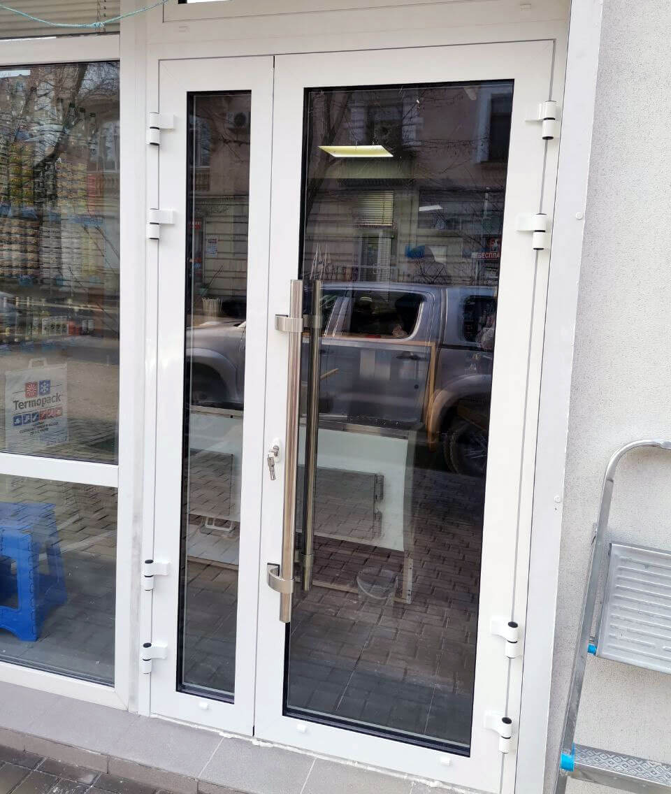 алюминиевая штульповая дверь Алютех ALT W62 белая установлена на входе в магазин